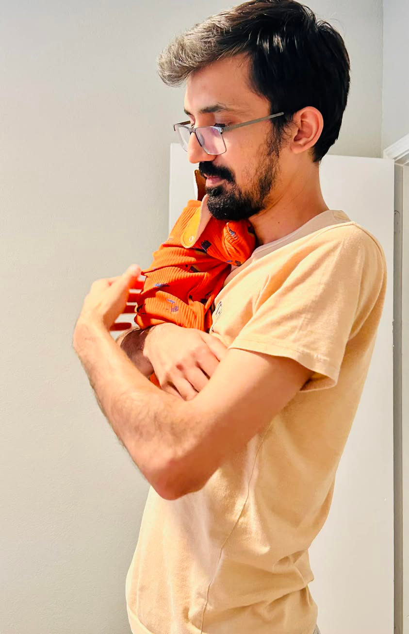 Umair holding his newborn son Raahim, 2024